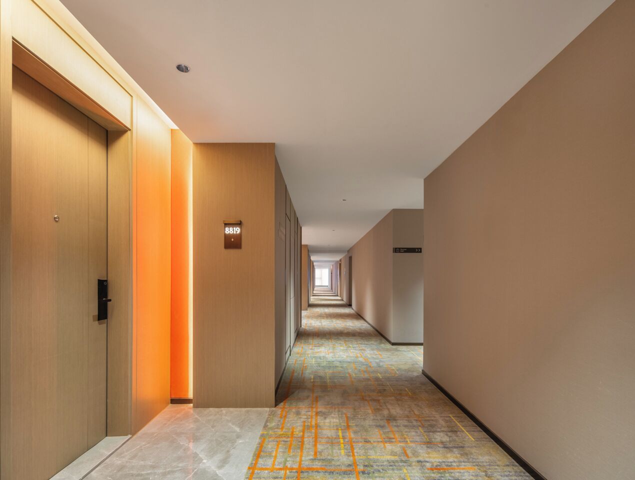 A hotel hallway with wooden doors, a carpeted floor, and a sign indicating room number 8819.