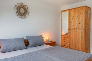 Ein Schlafzimmer mit einem Bett, zwei Kissen, einem Nachttisch mit einer Kerze und einem Holzschrank.