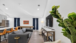 Una sala de estar moderna con un sofá gris, una mesa de centro y un televisor sobre un mueble.