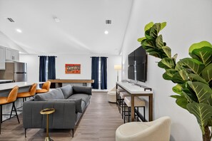 Ein modernes Wohnzimmer mit einem grauen Sofa, einem Couchtisch und einem Fernseher auf einem Schrank.