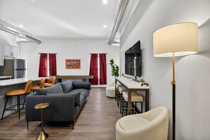 Ein modernes Wohnzimmer mit einer Couch, Sesseln, einem Couchtisch und einem Fernseher.