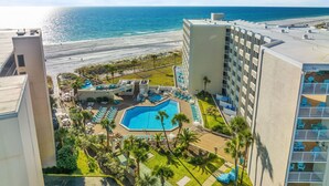 Ein Resort mit Swimmingpool, umgeben von Liegestühlen und Palmen, mit Blick auf einen Strand und den Ozean.