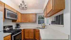 A kitchen with wooden cabinets, a microwave, a stove, and a chandelier.