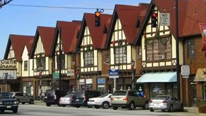 A row of traditional half-timbered buildings with various shops and signs, including a cinema and a pharmacy.