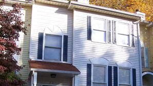 A two-story residential building with a front entrance, a small porch, and a visible mailbox.