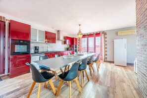 Una cucina moderna con pensili rossi, un tavolo da pranzo lungo e sedie nere.