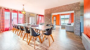 A spacious room with a long table, chairs, and a brick accent wall. - Holiday Home 'Sleeps 22 Brem Center with Large' (Brem-sur-Mer)