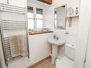 A bathroom with a towel rack, a sink, a toilet, a window, and a mirror. - Sheepwash Barn (Freshwater)