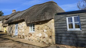 A traditional stone cottage with a thatched roof and wooden siding. - Sheepwash Barn (Freshwater)
