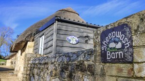 A rustic barn with a thatched roof, a sign reading "Sheepwash Barn," and a small window. - Sheepwash Barn (Freshwater)