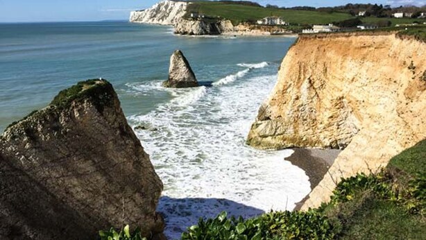 A coastal landscape with cliffs, a prominent rock formation, and a view of the sea. - Sheepwash Barn (Freshwater)