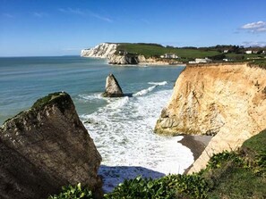 A coastal landscape with cliffs, a prominent rock formation, and a view of the sea. - Sheepwash Barn (Freshwater)