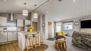 Una cocina moderna con una isla central, taburetes de bar y un comedor con mesa y sillas.
