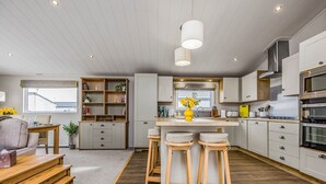 Una cocina moderna con una isla central, taburetes de bar y un comedor con mesa y sillas.