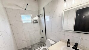 Une salle de bain équipée d’une douche, de toilettes, d’un lavabo et d’un miroir.