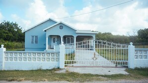Une maison bleu clair avec une clôture et une porte blanches.