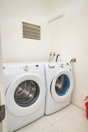Ein Waschraum mit zwei Waschmaschinen mit Frontlader und einem kleinen Fenster darüber.