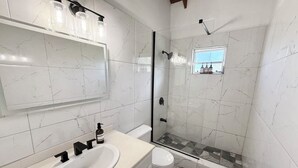 Une salle de bain avec un lavabo blanc, un miroir et un espace douche.