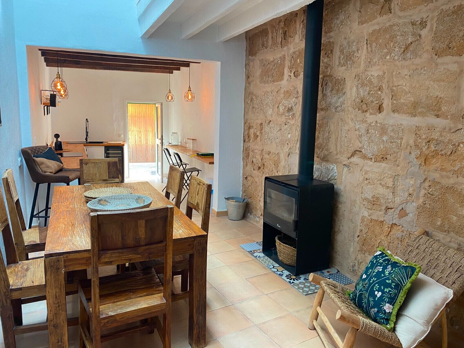 A cozy interior with a dining area, a stone wall, and a wood-burning stove.