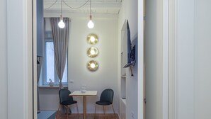 A narrow hallway with a wooden floor, a small table with two chairs, and a window with curtains. - Centro Bligny B - Lovely Studio in Bocconi Area (Milan)