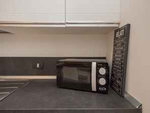 Eine moderne Küche mit integriertem Mikrowellenherd und einer an der Wand befestigten Speisekarte, die verschiedene Gerichte auflistet.