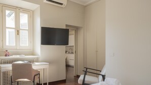 Una camera d'albergo con un letto, due poltrone, una scrivania, una TV e un armadio.
