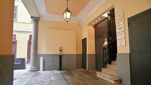 Un'hall dell'albergo con pavimento in pietra, una colonna imponente, una scala e un'apertura con indicazioni.
