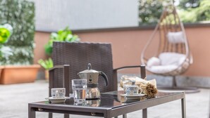 A table with a teapot, cups, and a glass set on an outdoor patio. - Palazzo Candiani - Deluxe Studio With Terrace (Milan)