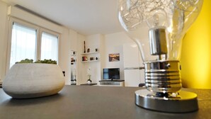 Una sala de estar moderna con un amplio ventanal, un televisor de pantalla plana y una lámpara decorativa.