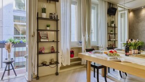 A modern dining area with a wooden table, chairs, and a bookshelf. - Cerva - Stylish 1 Bedroom Close to Duomo (Milan)