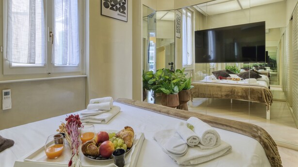 A hotel room with a bed, breakfast tray, and a TV. - Cerva - Stylish 1 Bedroom Close to Duomo (Milan)