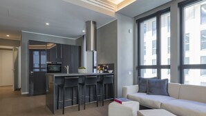 A modern kitchen with a central island, bar stools, and a large window providing natural light. - Central Tower S Babila - Elegant 2bdr With Rooftop Terrace (Milan)