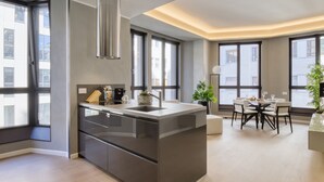 A modern kitchen with a central island, large windows, and a dining area with a table and chairs. - Central Tower S Babila - Elegant 2bdr With Rooftop Terrace (Milan)