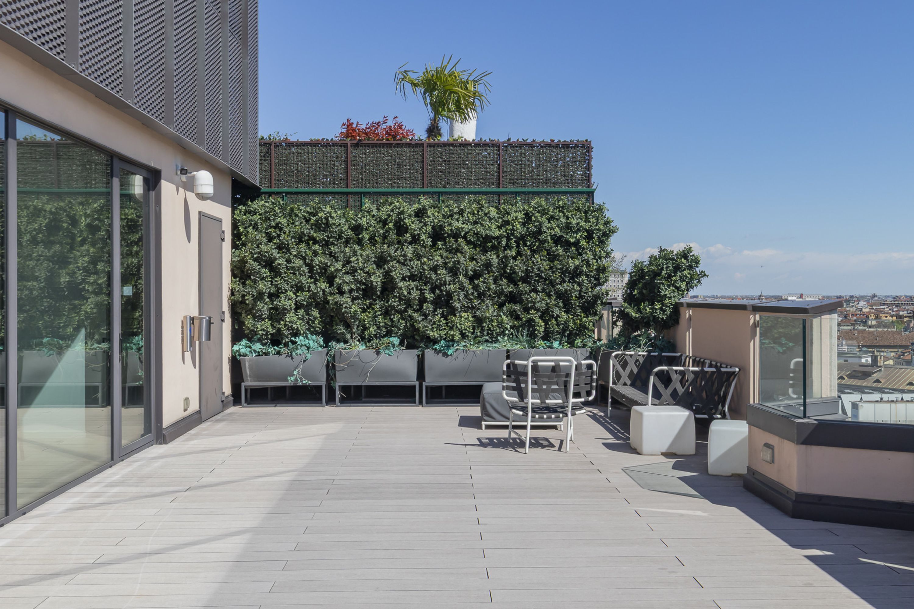 A rooftop terrace with a green wall, seating area, and a view of the city.