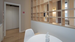 Ein Hotelzimmer mit einer Holzeinrichtungsanlage, einem weißen Tisch mit einer Wasserflasche und einer Tür zu einem weiteren Raum.