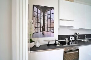 Een moderne keuken met witte kastjes, een zwart aanrecht en een groot raam met uitzicht op de stad.