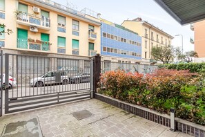 Un lotissement résidentiel fermé, avec une voiture garée, un bâtiment bleu et un portail vert.