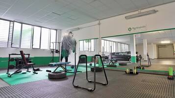 Un gimnasio con equipo de ejercicio, una colchoneta verde y un cartel de Rentopolis.
