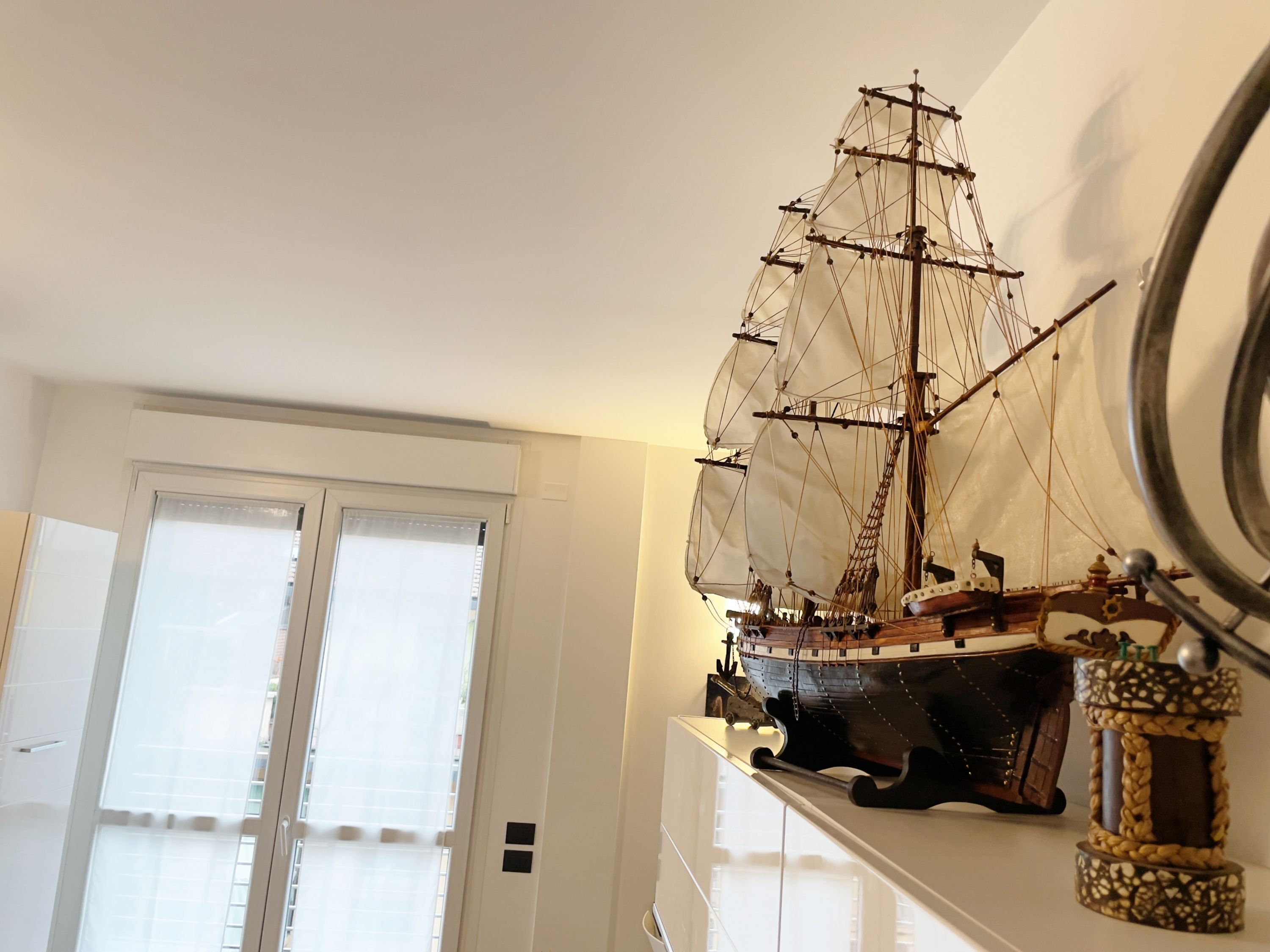 Una nave in miniatura su uno scaffale, una porta con un oblò e un oggetto fissato al muro.