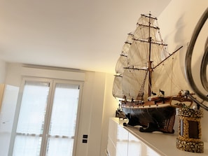 Un modèle de bateau sur une étagère, une porte avec une fenêtre et un objet fixé au mur.