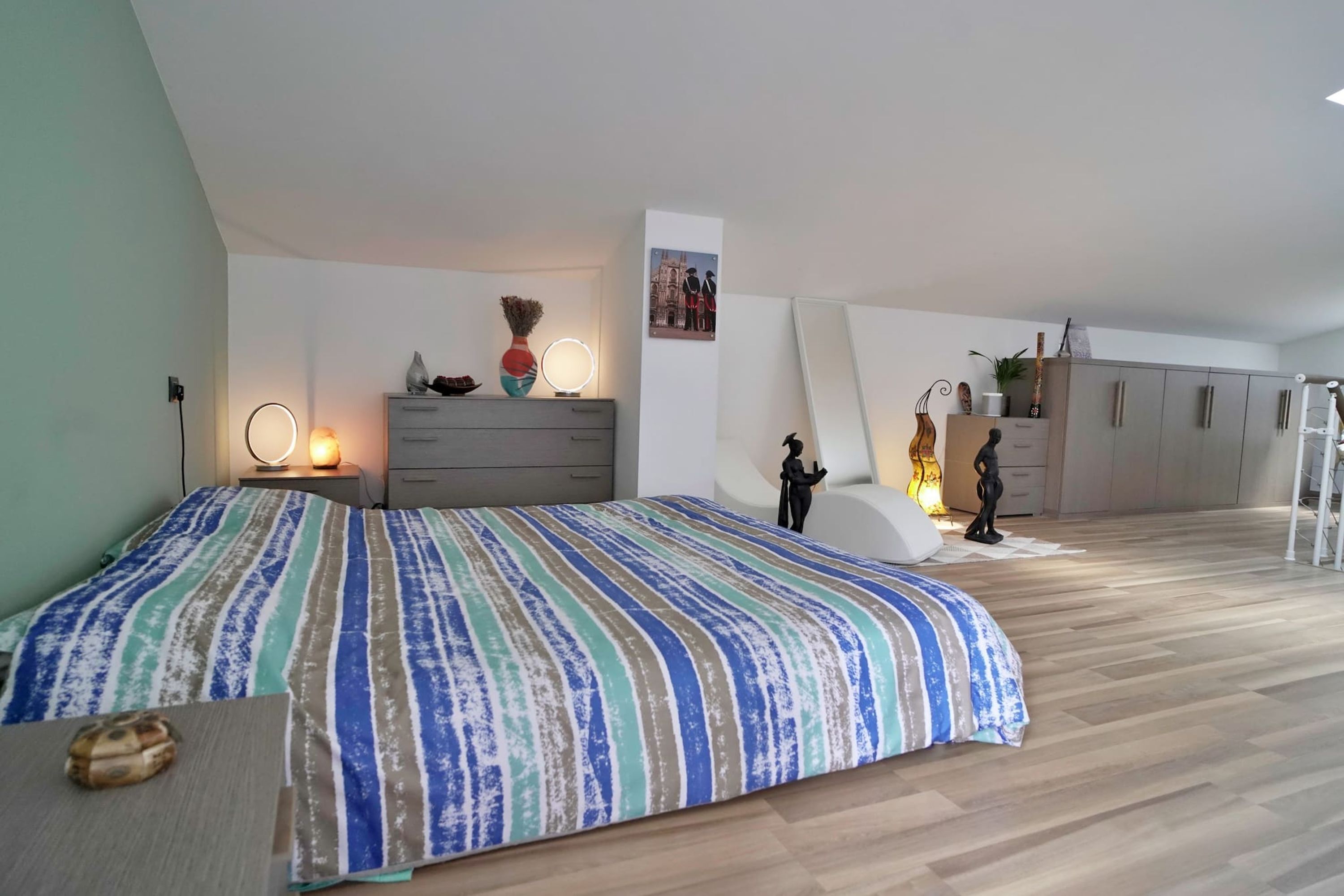 Una camera da letto con un letto grande, una cassettiera, una toeletta con specchio e un armadio.