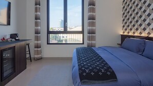Une chambre à coucher avec un lit, un bureau, une machine à café et une fenêtre avec des rideaux.