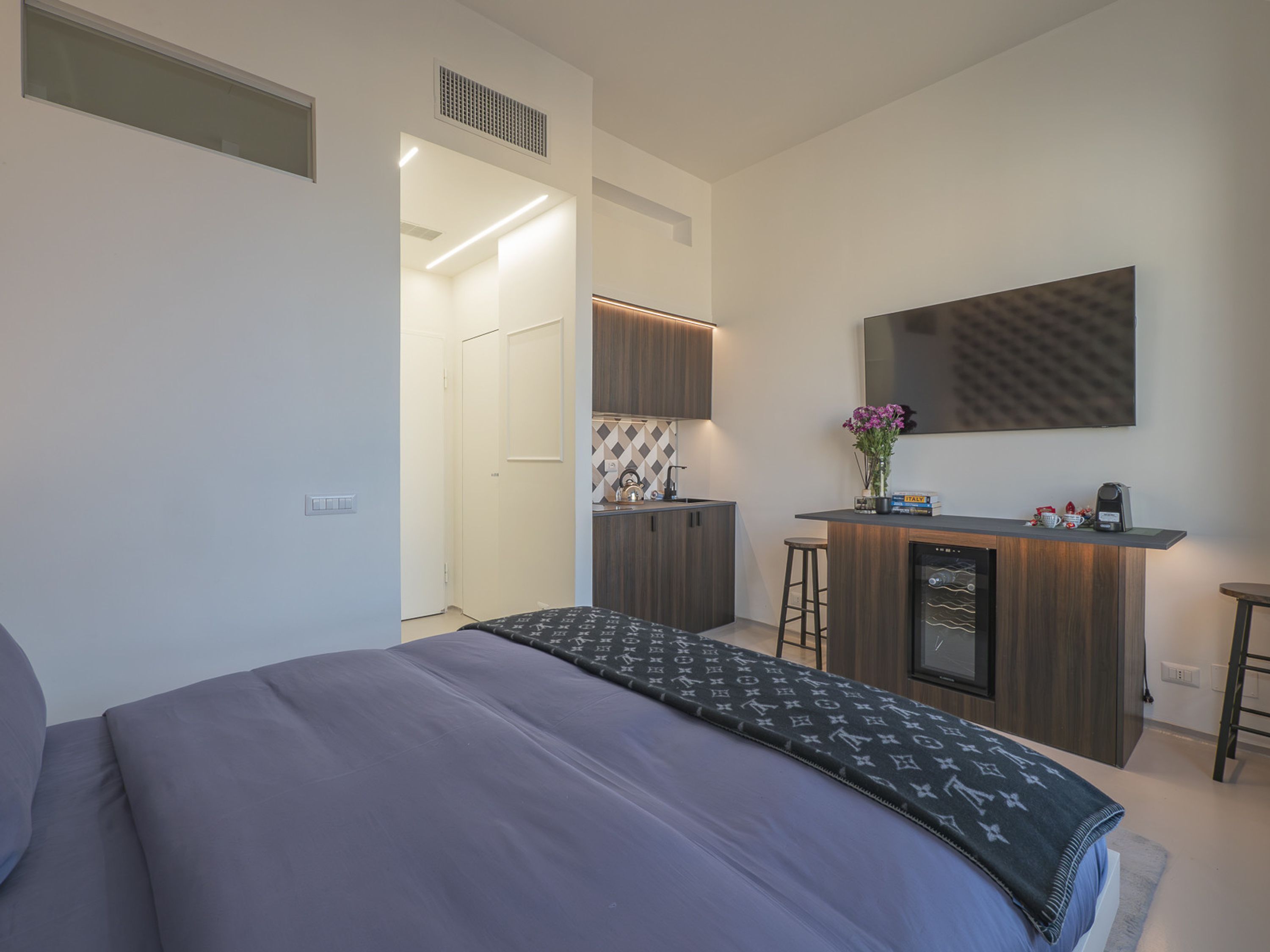 Ein modernes Hotelzimmer mit einem großen Bett, einer Küchenzeile, einer kleinen Bar und einem Badezimmer.