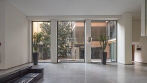 Un hall d’entrée spacieux au design moderne, comprenant un espace salon, de grandes fenêtres et des plantes en pot.