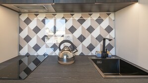 Une cuisine moderne avec un revêtement mural géométrique, une bouilloire, un évier et un plan de travail.