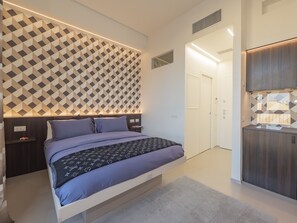 Une chambre moderne avec un mur orné d’un motif géométrique, un lit avec une couette à motifs, une table de chevet et une armoire intégrée.