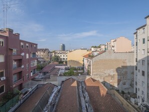 Une vue sur un paysage urbain avec de nombreux bâtiments, dont un bâtiment rose bien visible à gauche et un bâtiment beige au centre.