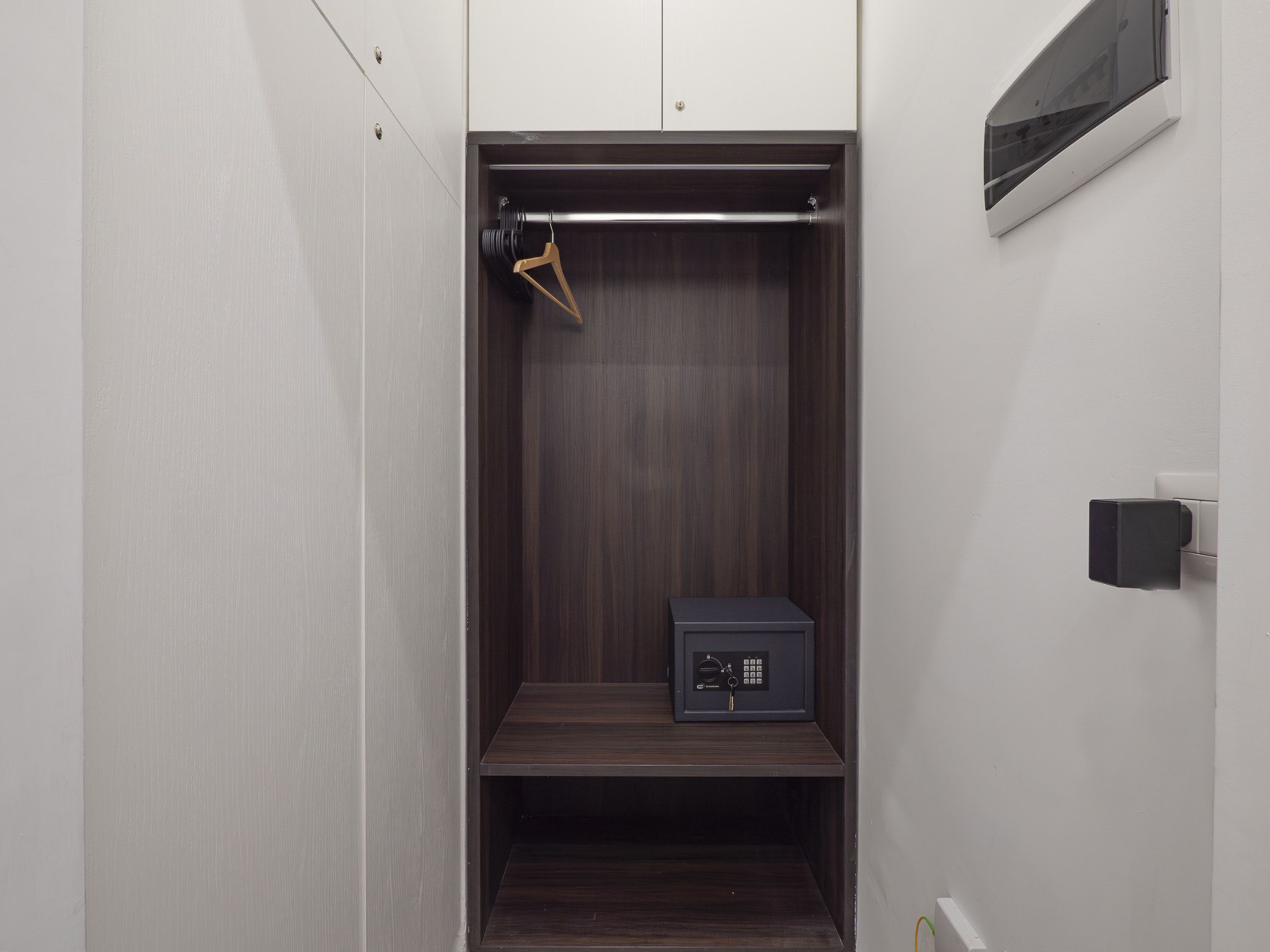 Un dressing avec des finitions en bois foncé, une tringle et un petit coffre-fort.