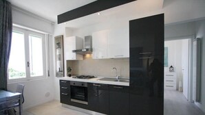 Une cuisine moderne avec des meubles de rangement noirs et blancs, un four encastré et une grande fenêtre qui laisse entrer la lumière naturelle.