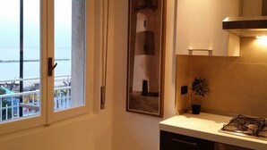 Une cuisine équipée d’une cuisinière à gaz, d’une plante en pot et d’un tableau encadré représentant un phare.